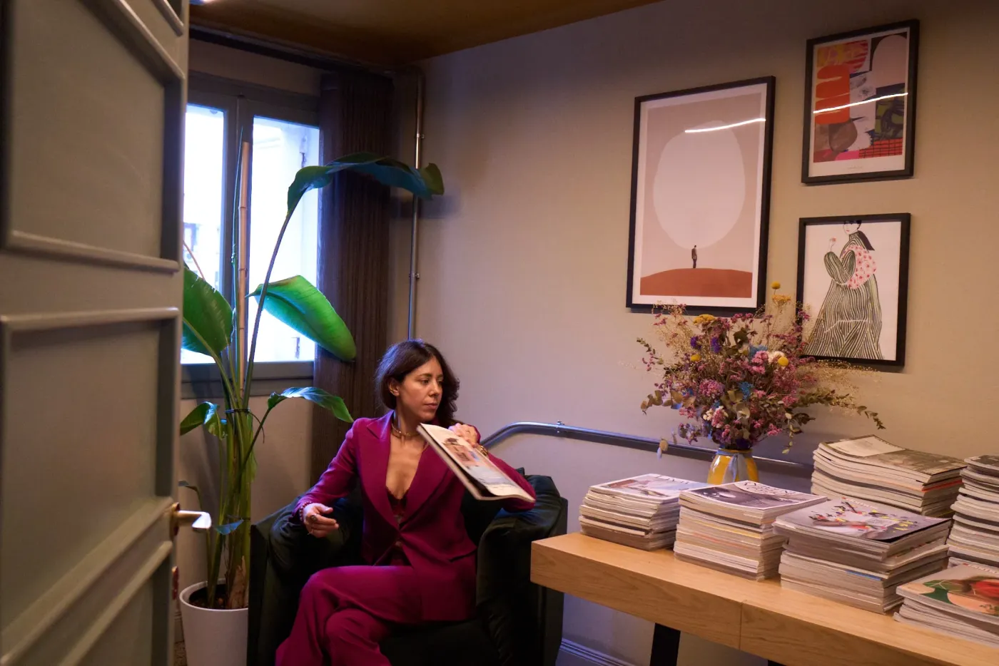 Angolo studio con poltrona verde, riviste e opere d'arte